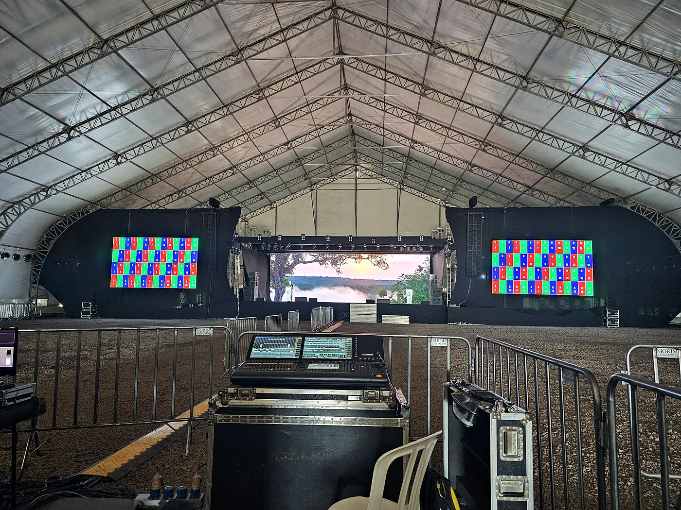 Palco montado com telões de LED e mesa de som dentro da tenda